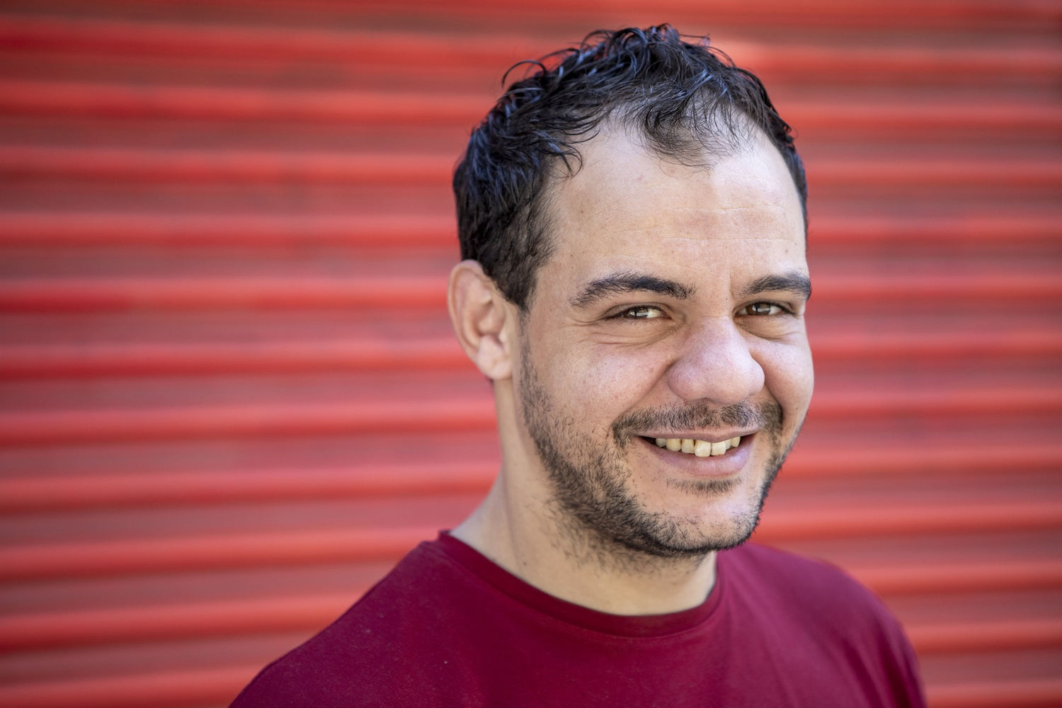 Man smiling at camera with a red background.