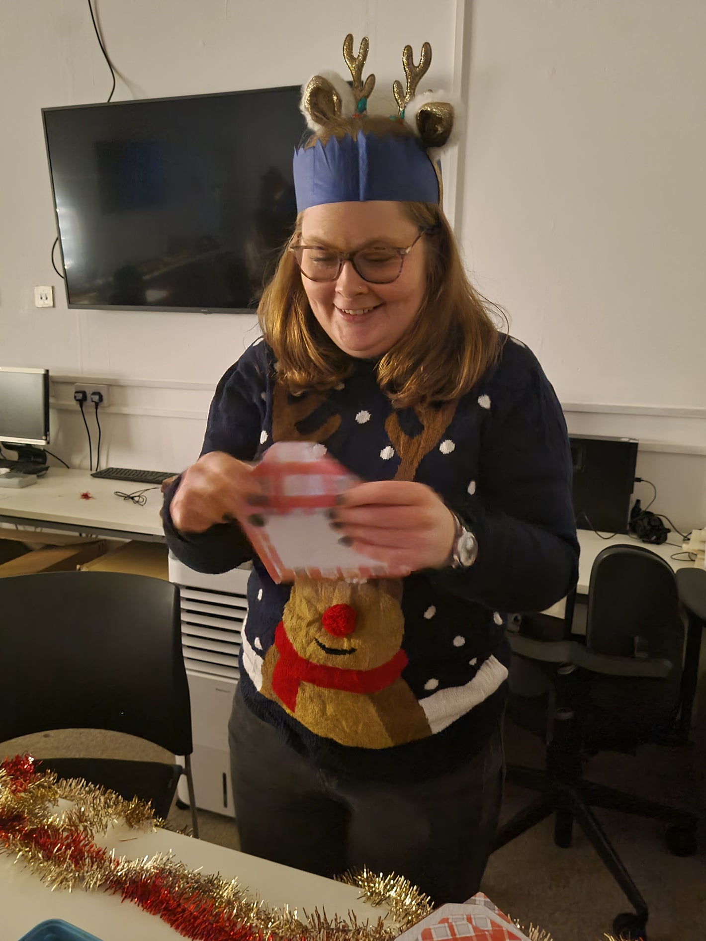 Staff member dressed up in Christmas attire sealing a Christmas card.