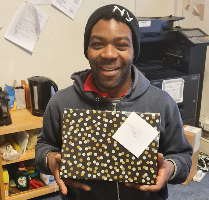Man smiling holding a Christmas gift.