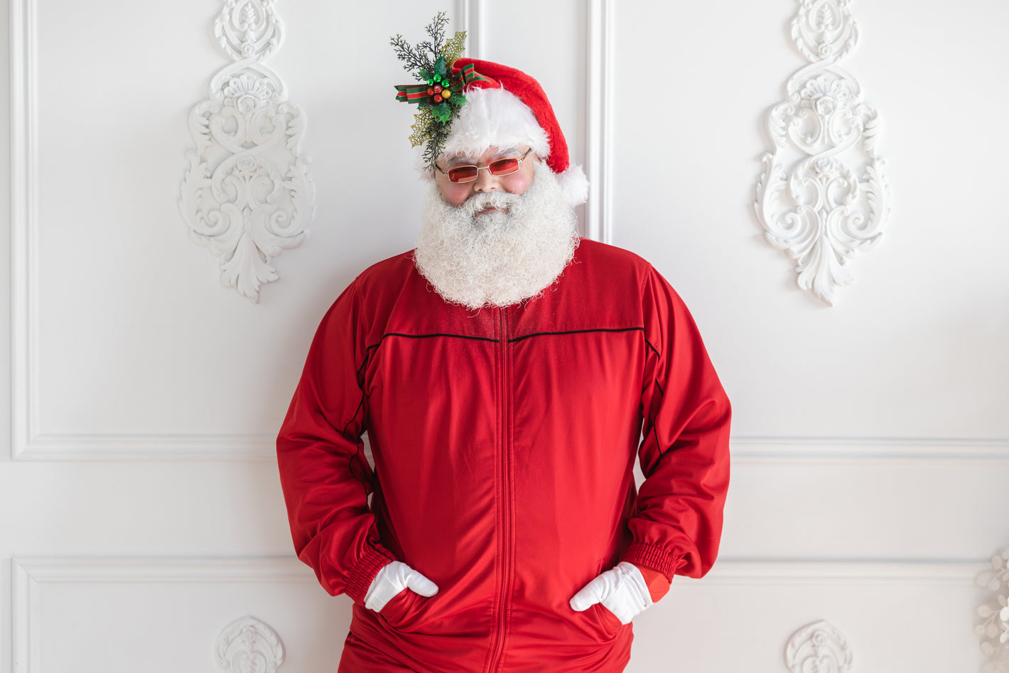 Man dressed as Santa in a red tracksuit with red sunglasses on and a Santa hat.