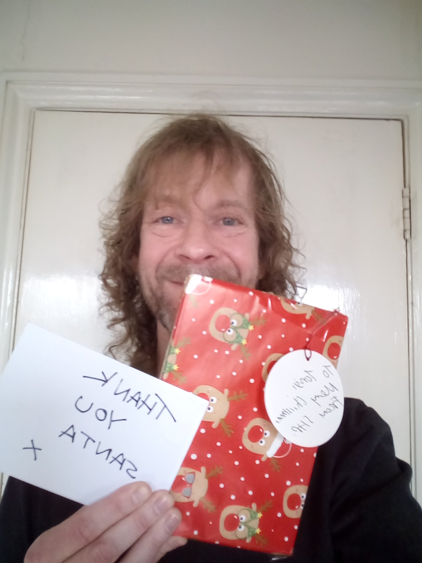 Man smiling holding a Christmas gift and a card.