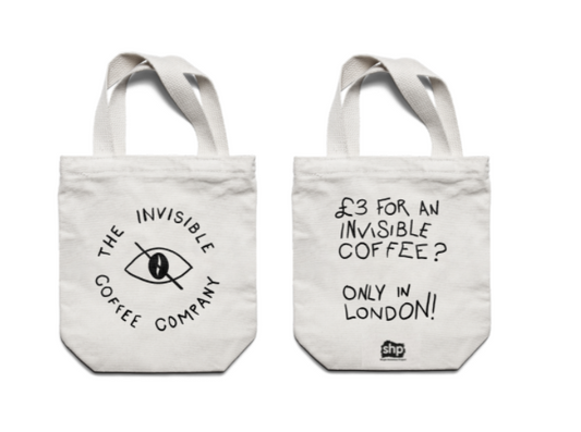 Two of the Invisible Coffee Company tote bags. One with the company logo, the other with "£3 for an invisible coffee? Only in London! SHP" on.
